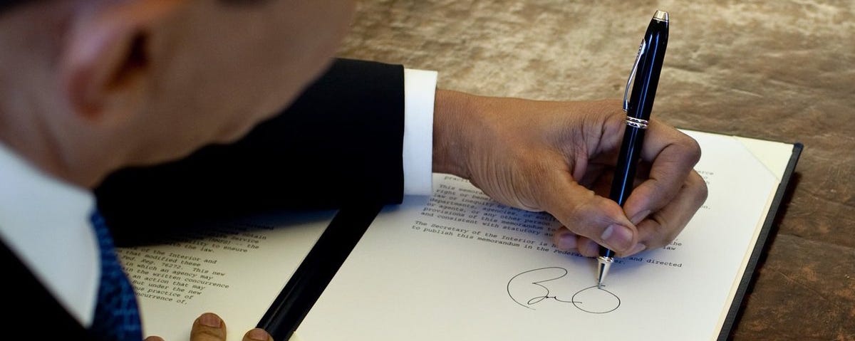 President Obama signing a document with a Cross pen