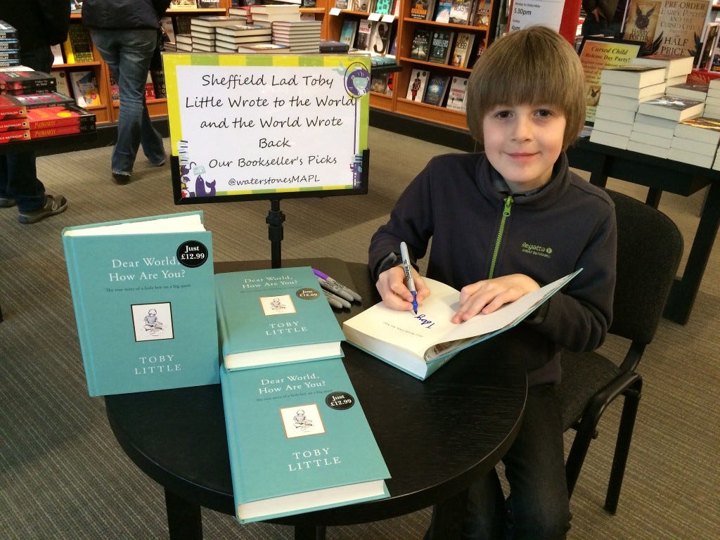 Toby signing copies of his book, Dear World, How Are You?